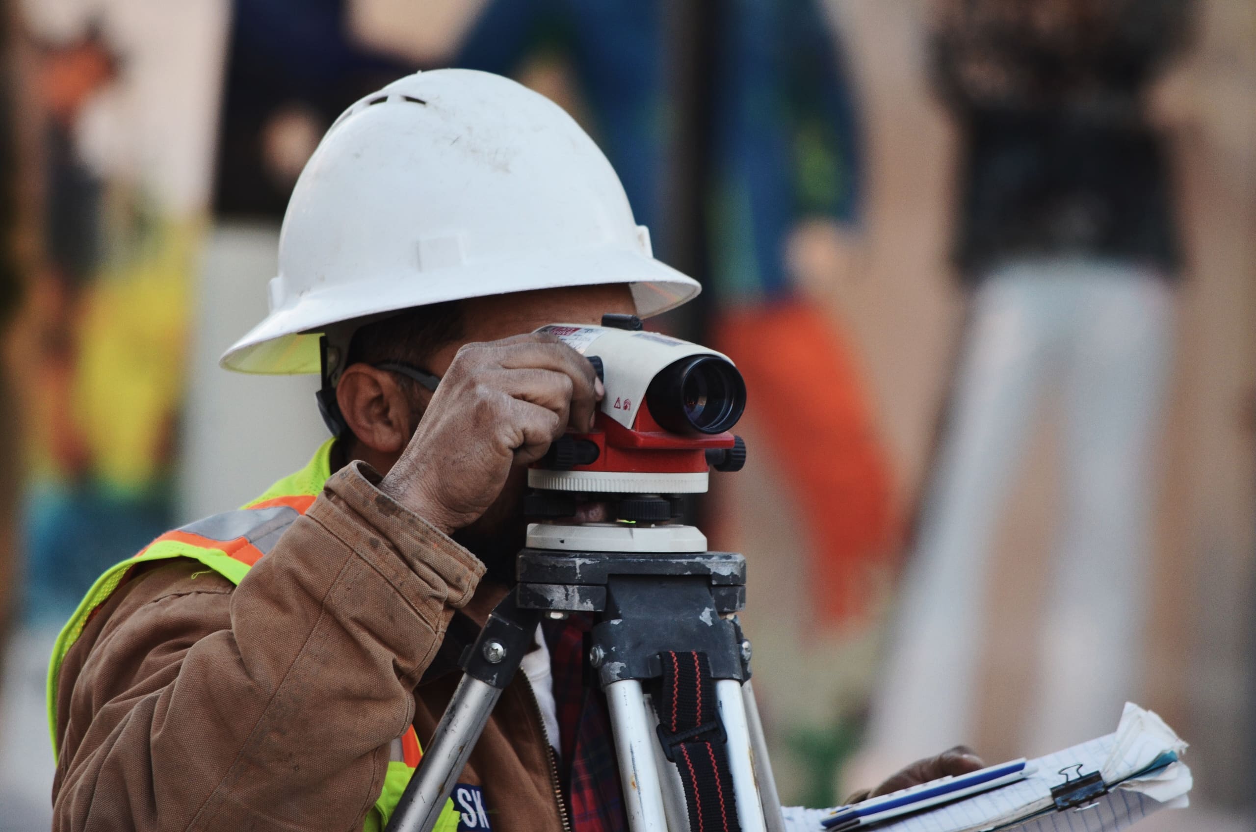 Site surveyor sighting through a level on an active JULY build site