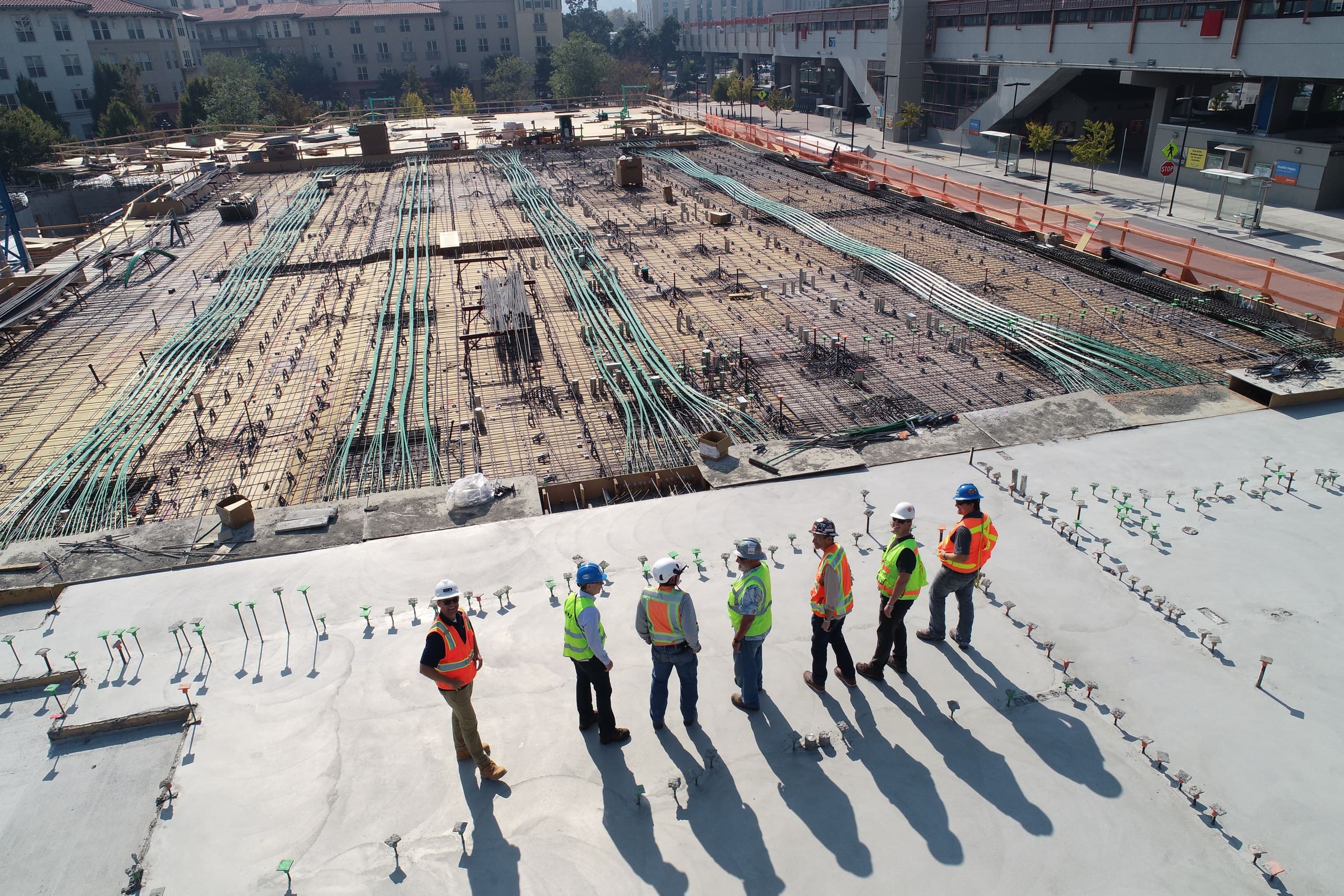 Construction crew standing on a freshly poured concrete deck above a large building site