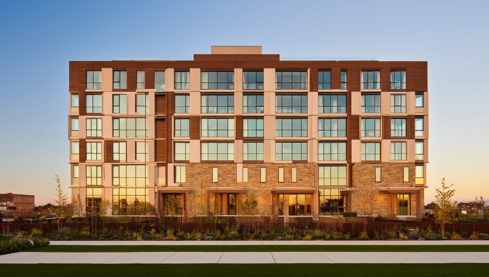 A newly completed multiplex residential building glowing with warm light at golden hour